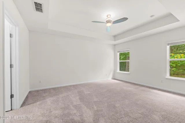 an empty room with windows and fan