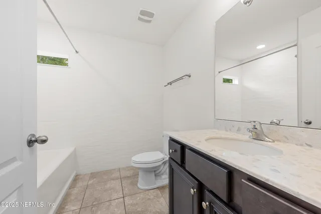 a bathroom with a granite countertop sink a toilet and a mirror
