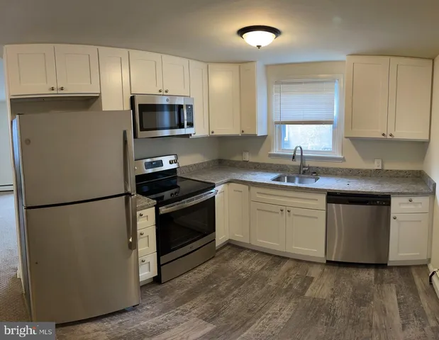 a kitchen with granite countertop a refrigerator stove a sink and dishwasher with wooden floor