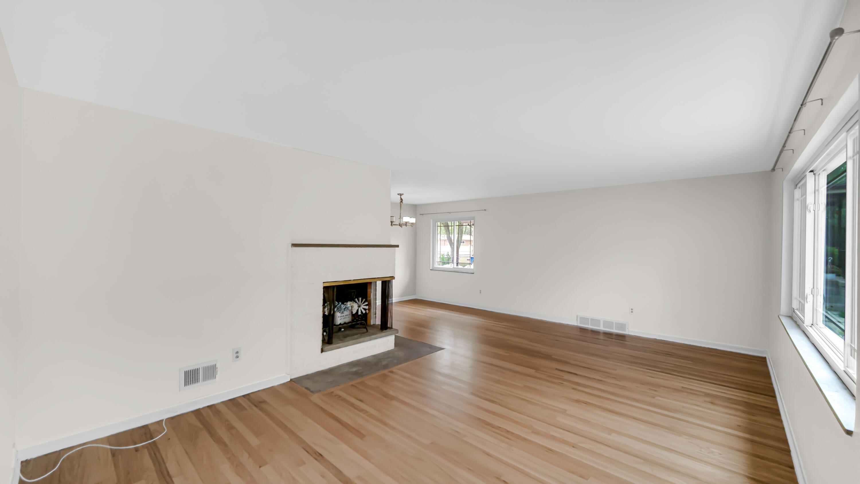 6957 Ash Avenue Gary, IN 46403 - Photo 3 of 22 an empty room with wooden floor fireplace and windows