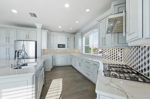 a kitchen with granite countertop white cabinets stainless steel appliances and chairs