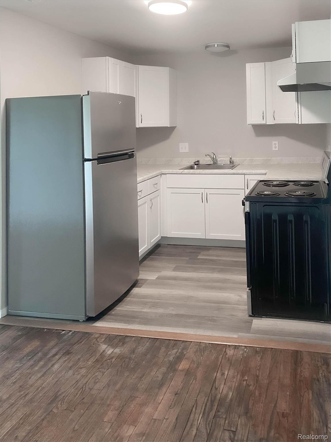 32650 Mound Road, Unit 4 Warren, MI 48092 - Photo 25 of 32 Kitchen featuring white cabinetry, a stainless steel refrigerator, a black electric range, and wood-finish flooring