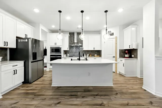 a kitchen with stainless steel appliances kitchen island granite countertop a refrigerator a stove and a sink