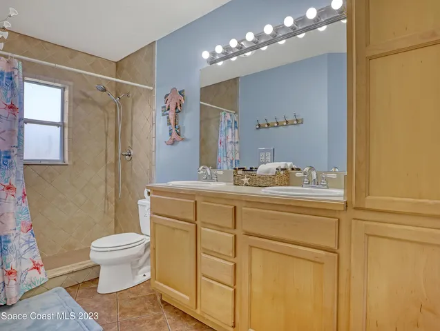 a bathroom with a sink a toilet a mirror a vanity and shower