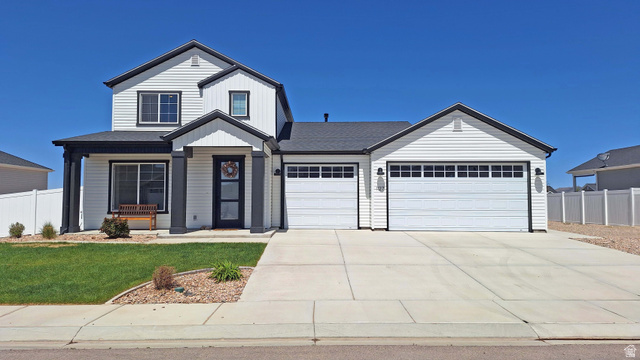 1127 4240 North Enoch, UT 84721 - Photo 2 of 56 View of front facade featuring board and batten siding, a garage, concrete driveway, covered porch, and a shingled roof