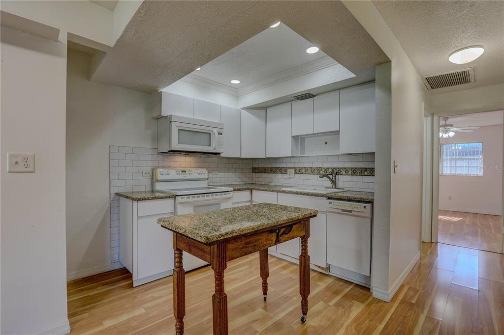 864 Lake Haven Road Dunedin, FL 34698 - Photo 9 of 28 a kitchen with stainless steel appliances granite countertop a stove top oven a sink and dishwasher a refrigerator with wooden floor