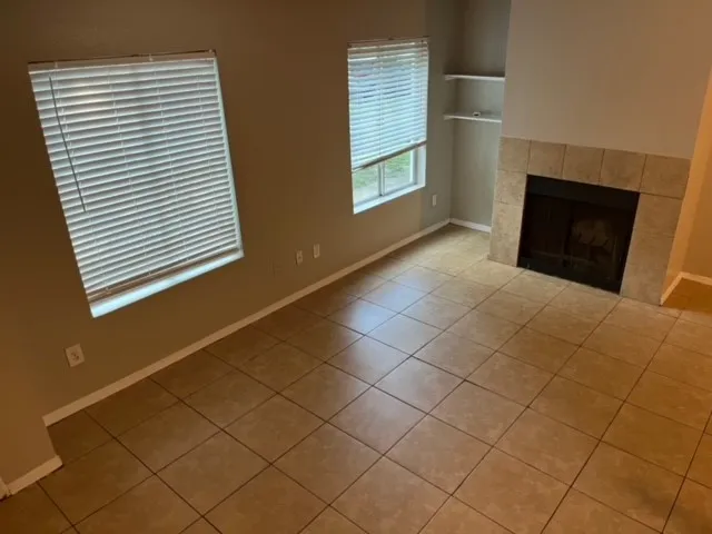 a view of an empty room with wooden floor and a fireplace