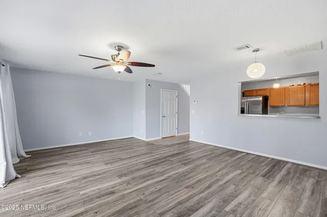 a view of a room with wooden floor and a ceiling fan