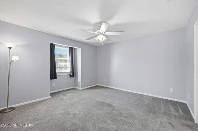an empty room with fan and windows