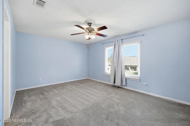 an empty room with windows and ceiling fan