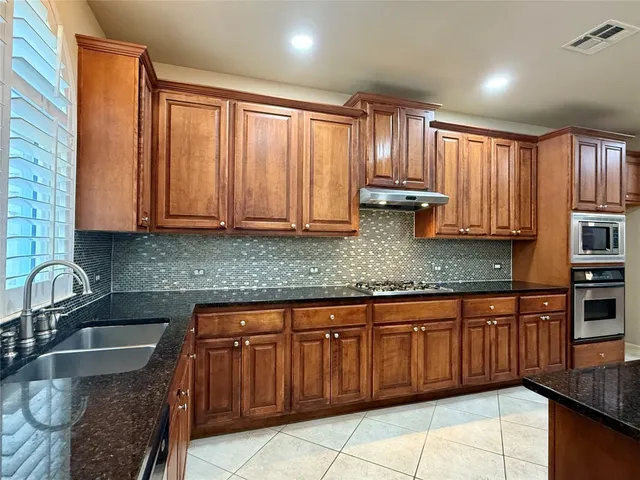 a kitchen with stainless steel appliances granite countertop wooden cabinets a sink and dishwasher
