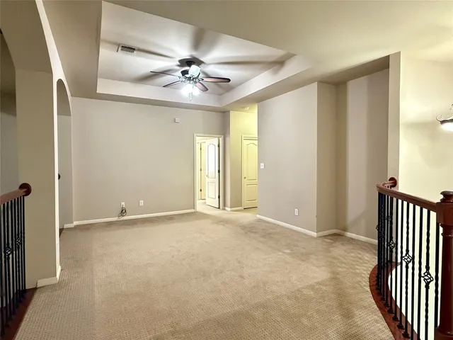 an empty room with a chandelier fan and windows