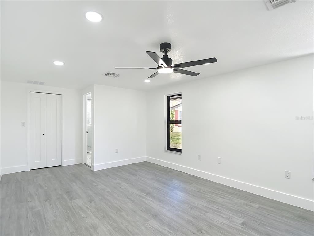 8130 San Felipe Court Port Richey, FL 34668 - Photo 22 of 54 an empty room with wooden floor fan and windows