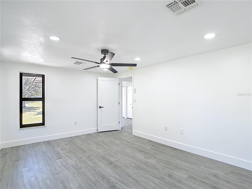 8130 San Felipe Court Port Richey, FL 34668 - Photo 24 of 54 an empty room with wooden floor ceiling fan and windows