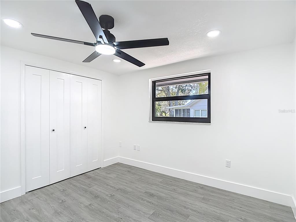 8130 San Felipe Court Port Richey, FL 34668 - Photo 35 of 54 an empty room with wooden floor ceiling fan and windows