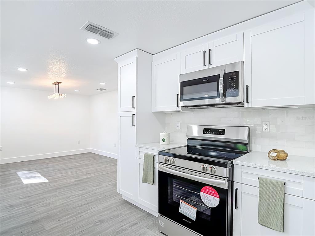 8130 San Felipe Court Port Richey, FL 34668 - Photo 9 of 54 a kitchen with stainless steel appliances granite countertop a stove a microwave and a refrigerator
