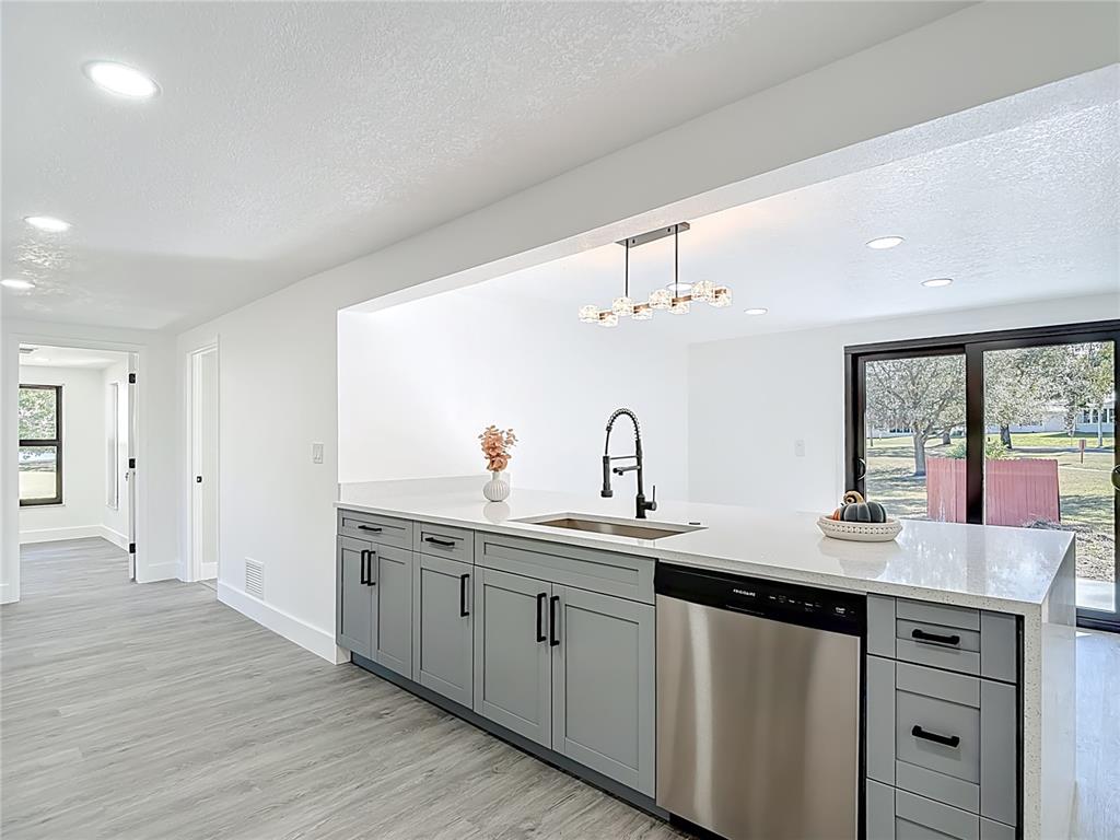 8130 San Felipe Court Port Richey, FL 34668 - Photo 10 of 54 a kitchen with a sink dishwasher and white cabinets with wooden floor