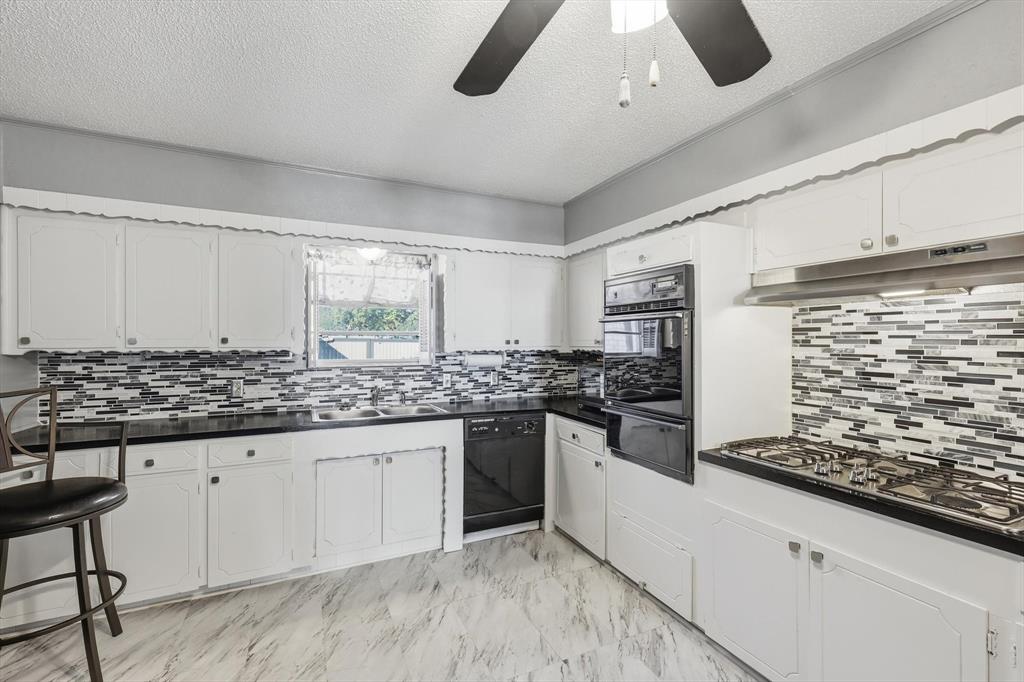 910 Rockwall Street McKinney, TX 75069 - Photo 11 of 34 Kitchen featuring dark countertops, tasteful backsplash, a textured ceiling, and white cabinetry