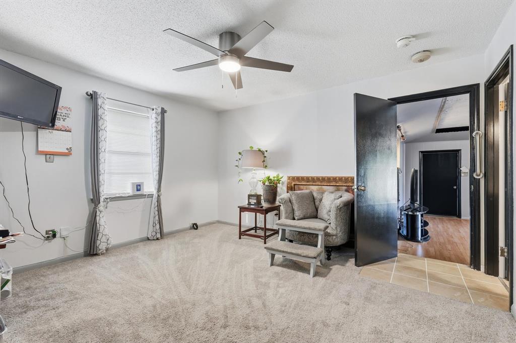 910 Rockwall Street McKinney, TX 75069 - Photo 16 of 34 Living area with a textured ceiling, light colored carpet, and a ceiling fan