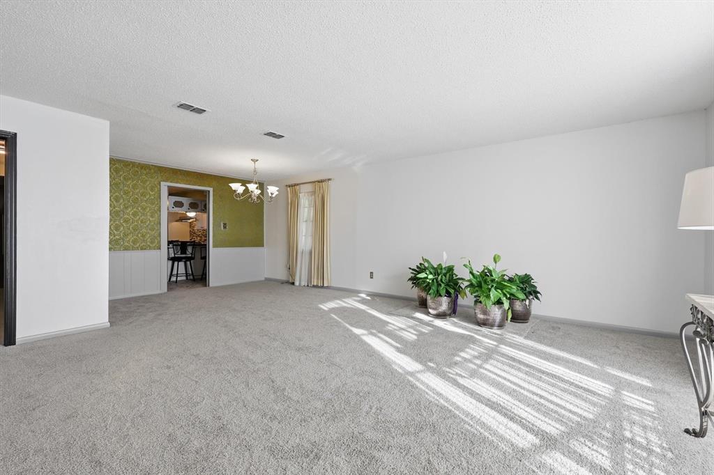 910 Rockwall Street McKinney, TX 75069 - Photo 6 of 34 Unfurnished room featuring wallpapered walls, a wainscoted wall, a textured ceiling, light colored carpet, and a chandelier