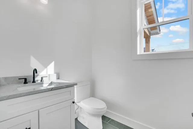a bathroom with a granite countertop toilet sink and mirror