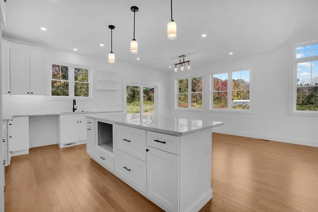 a large white kitchen with kitchen island white cabinets and a wooden floor