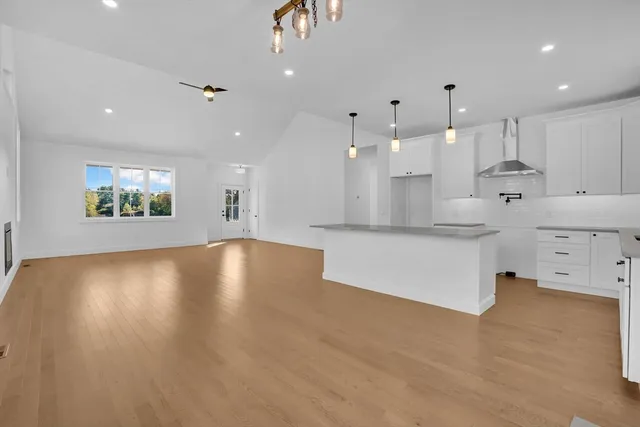 a large kitchen with stainless steel appliances granite countertop a stove a sink a refrigerator and white cabinets with wooden floor