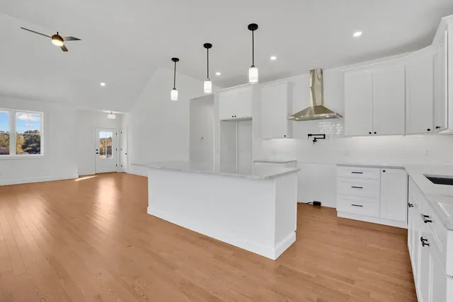 a large kitchen with stainless steel appliances a large counter top a sink a refrigerator and a stove