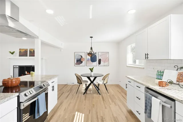 a kitchen with stainless steel appliances granite countertop a stove top oven a sink dishwasher and white cabinets with wooden floor