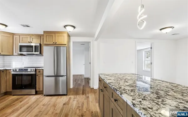 a kitchen with stainless steel appliances granite countertop a refrigerator a stove and a sink