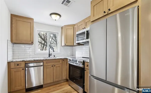 a kitchen with stainless steel appliances granite countertop a sink a stove a refrigerator a washer and dryer
