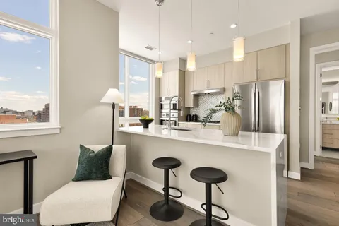 a kitchen with stainless steel appliances kitchen island a table chairs in it and wooden floors
