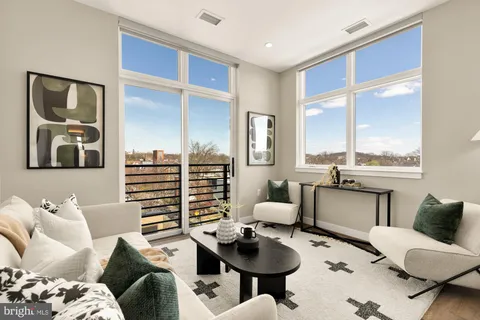 a living room with furniture kitchen view and large windows