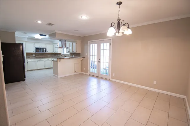 a open kitchen with kitchen island granite countertop a refrigerator a sink dishwasher a stove and white cabinets with wooden floor