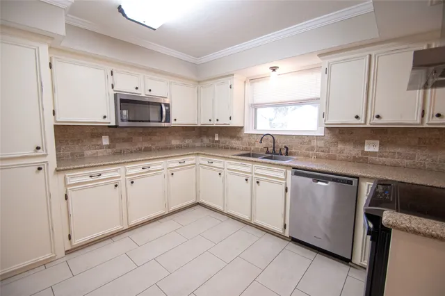 a kitchen with cabinets appliances a sink and a window