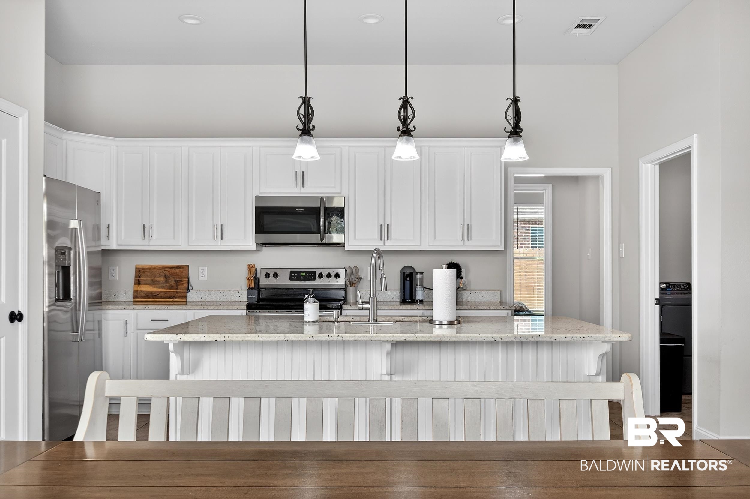 1084 Stella Road Foley, AL 36535 - Photo 11 of 31 Kitchen featuring light stone counters, white cabinetry, stainless steel appliances, a kitchen island with sink, and a kitchen bar