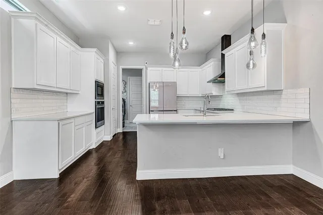 a kitchen with stainless steel appliances granite countertop a sink a stove and a wooden floors