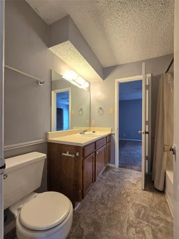 a bathroom with a granite countertop toilet sink and mirror
