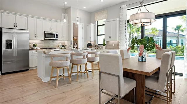 a dining room with stainless steel appliances a dining table wooden floor and a refrigerator