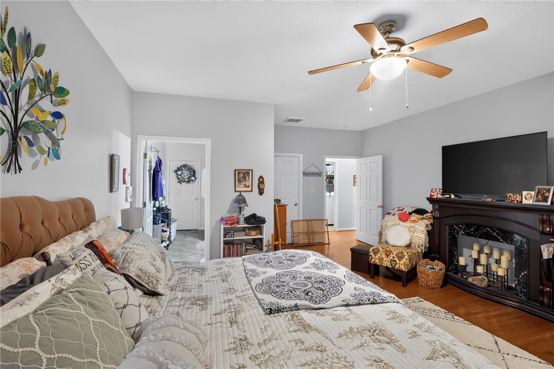 144 Elliott Circle Anderson, SC 29621 - Photo 22 of 30 A well-lit bedroom features hardwood floors and a ceiling fan, with an elegant fireplace creating a focal point.