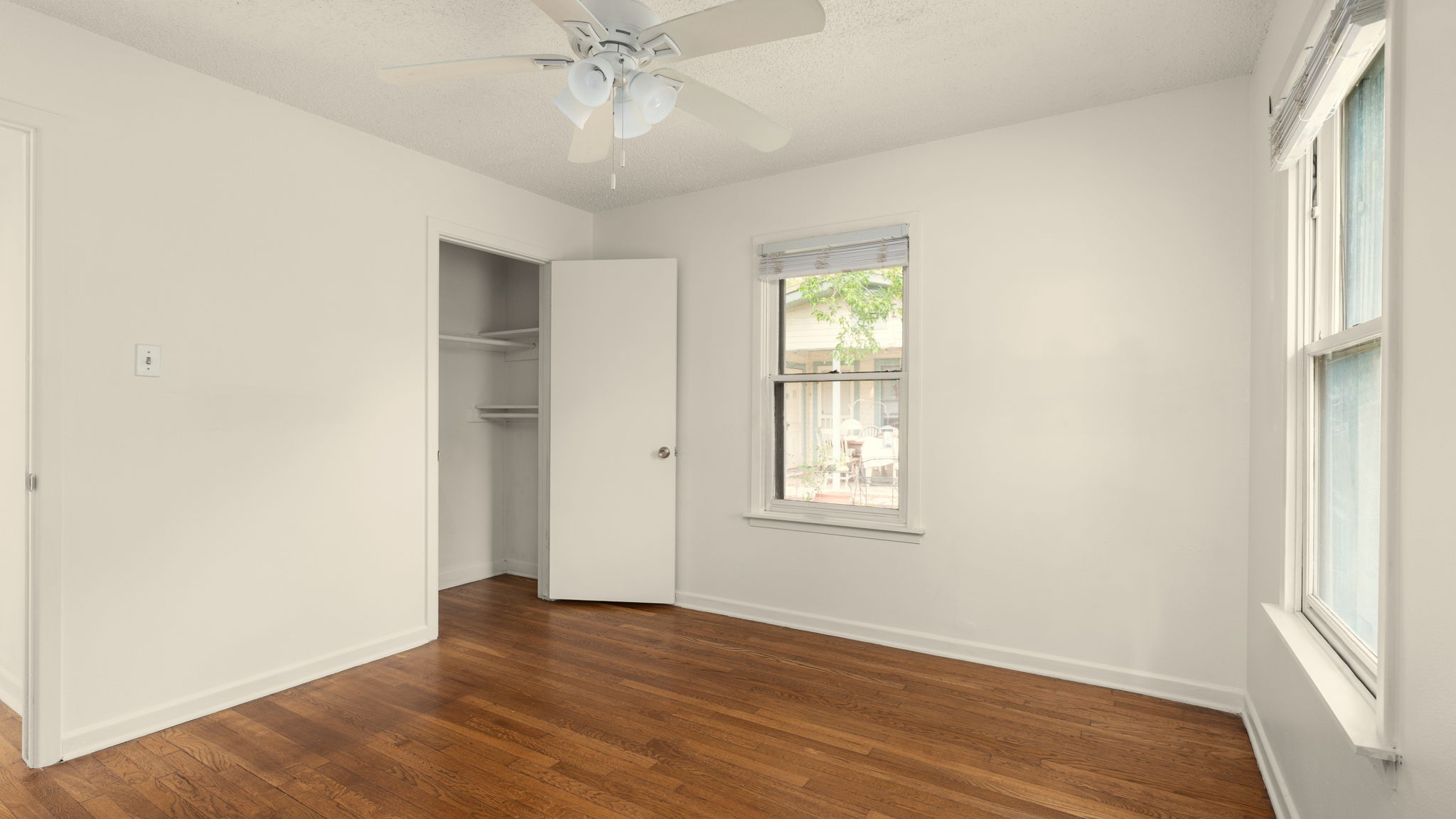206 East Skyview Road Austin, TX 78752 - Photo 21 of 32 Hardwood flooring extends throughout this well-lit bedroom, offering both charm and function.