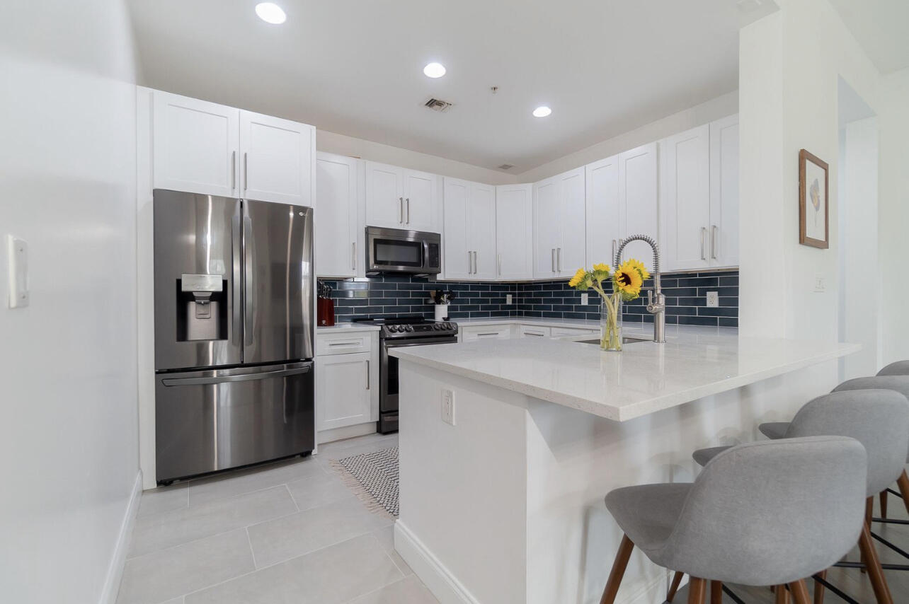 a kitchen with stainless steel appliances a refrigerator a sink a stove a table and chairs