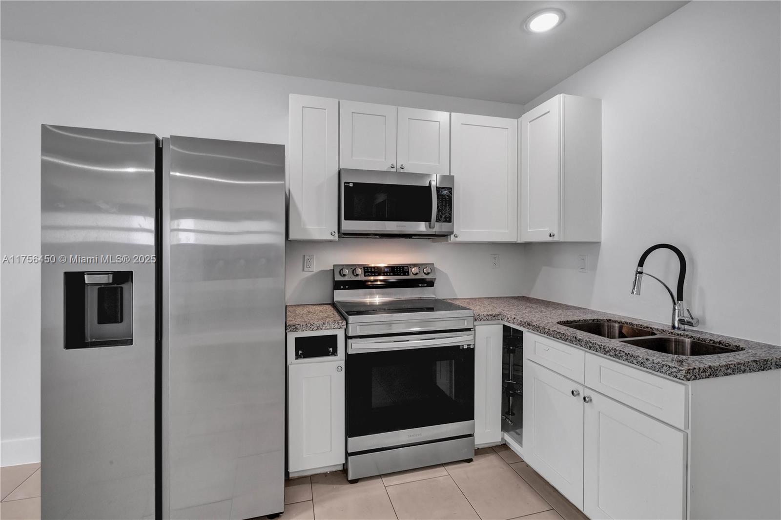 1749 Northwest 64th Street, Unit A Miami, FL 33147 - Photo 3 of 19 a kitchen with white cabinets and stainless steel appliances