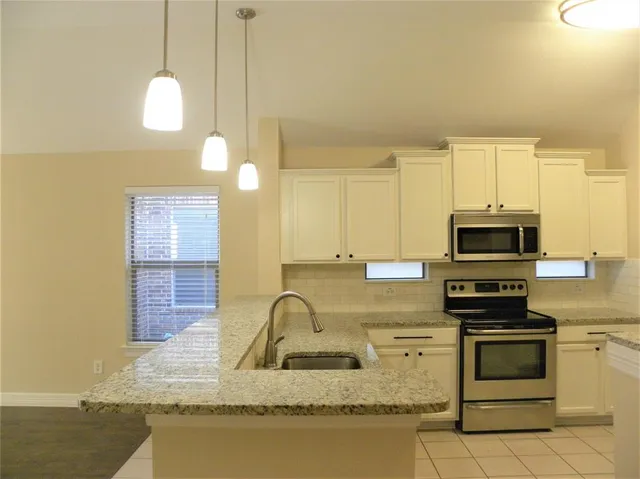 a kitchen with kitchen island granite countertop a stove a sink and a microwave