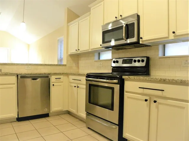 a kitchen with stainless steel appliances granite countertop a stove a microwave and a white cabinets