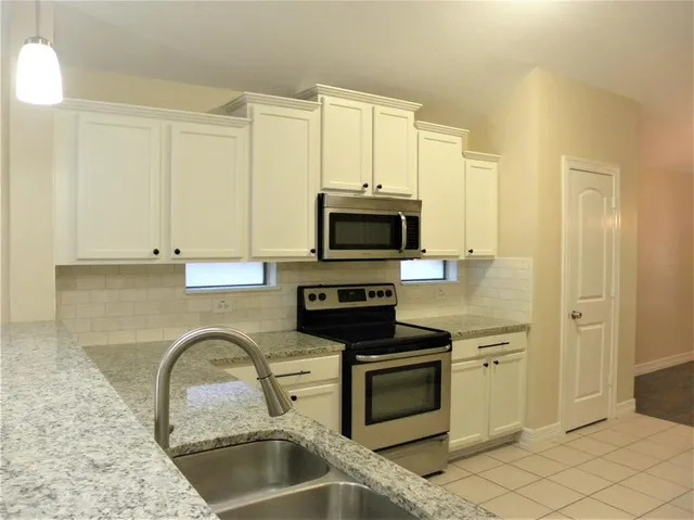 a kitchen with stainless steel appliances granite countertop a stove a microwave and a sink