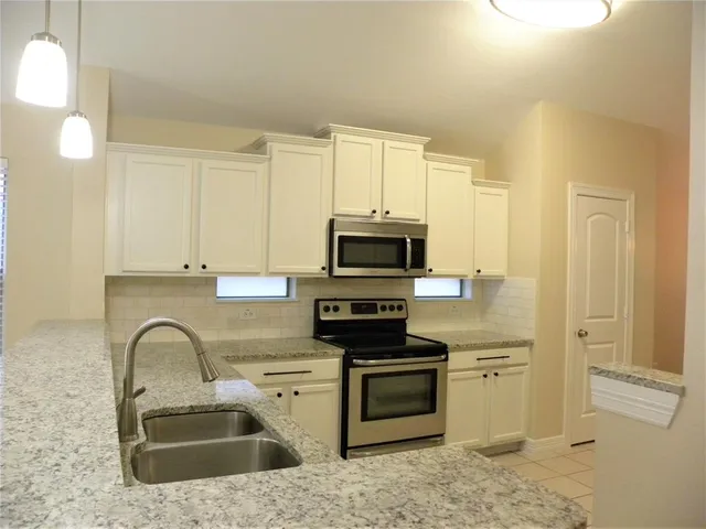 a kitchen with stainless steel appliances granite countertop a stove a sink and a microwave