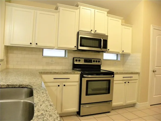 a kitchen with stainless steel appliances granite countertop a stove a microwave and a sink