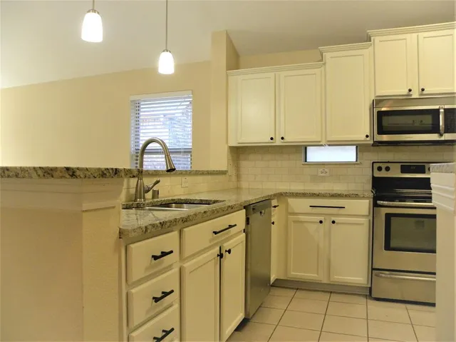 a kitchen with stainless steel appliances granite countertop a stove a sink and a microwave