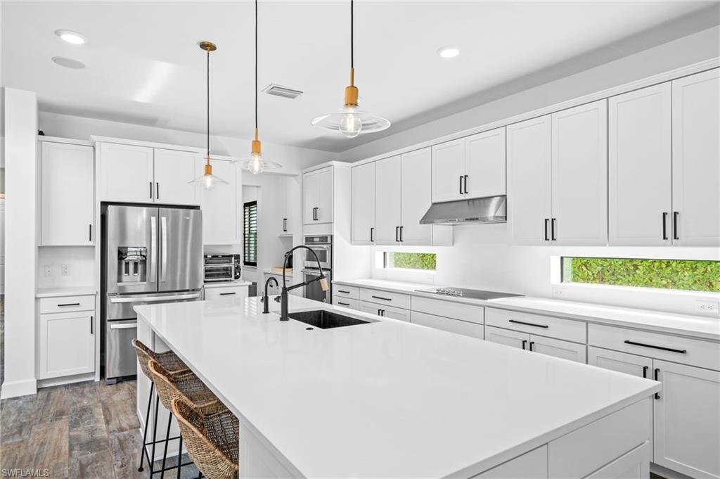19836 Beverly Park Road Estero, FL 33928 - Photo 12 of 40 a kitchen with kitchen island a stove a sink a center island and windows